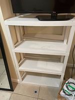 Front view of white plastic shelving unit with four shelves