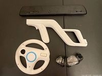 Top view showing black sensor bar, white Wii shooter gun shell, white steering wheel shell, clear wired Nunchuk
