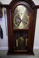 Full view of wood wall clock hanging on wall