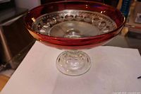 Side view of clear glass pedestal compote with ruby band