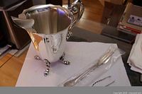 Pitcher, fork in sleeve, tongs visible on paper towel