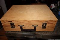 closed wooden artist case front view showing latches and handle