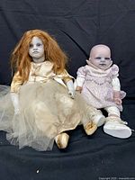 Both spooky dolls seated side by side
