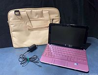 Pink HP Mini laptop open with charger and beige case