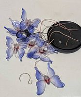 Cluster of blue butterflies attached to wiring, black mounting cap visible, S-hook separate