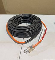 Coiled 100ft Heatit JHSF pipe heating cable showing orange lead and grounded plug