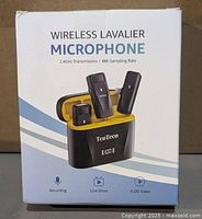 Front of sealed retail box showing TeoTeeo wireless lavalier microphone kit, graphics of two mics and charging case, product specs