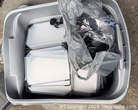 Grey tote containing stack of translucent white plastic panels and bag of black connectors for cubby assembly
