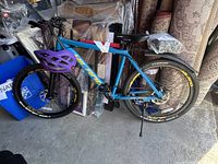 Full view of blue HILAND mountain bike with purple helmet attached and yellow-lettered tires