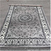 Full view of grey and white oriental rug unrolled on ground showing pattern and border