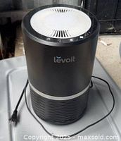 Front angled view of the Levoit air purifier showing brand logo, top vent and attached power cord