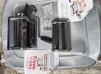 All components laid out: pasta maker body, cutter attachment, crank, clamp, manual