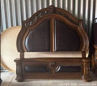 Front view of carved wood headboard and leather panels