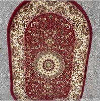 Full view of oval red and beige area rug showing pattern and condition