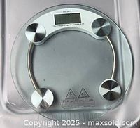 Top view of the round glass digital scale showing LCD, four metal sensors, model marking