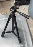 Overall view of black tripod standing fully extended on surface