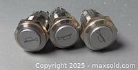 Front view of three silver horn push buttons showing horn icons on actuator faces