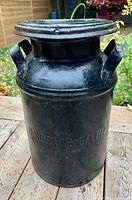 Full view of black metal milk jug with lid attached