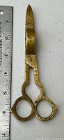 Full view of brass candle snuffer scissors beside ruler showing ~6 in. length