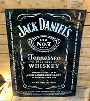 Full view of Jack Daniel's tin advertising sign leaning against wall
