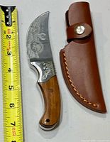 Knife and sheath beside tape measure showing size