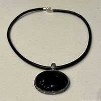 Full view of necklace showing leather cord, clasp and pendant