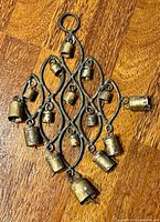 Full view of brass wind chime on wood surface