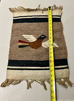 Full view of rug displaying bird motif, stripes and fringe