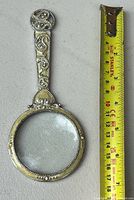 Full view of magnifying glass beside tape measure showing length ~6.5 in