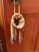 Front view of small woven basket hanging from door knob, showing buckskin fringes and metal cones