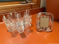 Stack of four clear lucite handkerchief bowls beside clear lucite photo frame