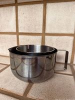 Two nested stainless steel bowls showing exterior and handle