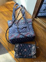 Blue paisley tote and dark floral clutch on wooden surface