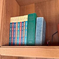 Shelf with eight Popular Mechanics Home Handyman volumes 1-8, a green Encyclopedia of Child Care and Guidance, and a grey-blue clothbound book