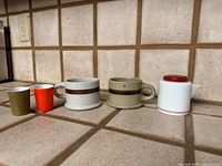 All five pieces lined up: two mugs, two small cups, porcelain creamer