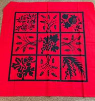 Full view of square red tablecloth with black printed design