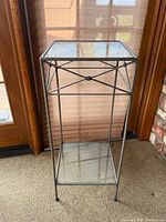 Full view of wrought iron stand showing glass top and lower shelf