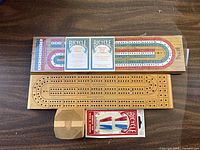 overview showing two cribbage boards, three sealed Bicycle card decks, blister pack of six metal pegs, paper envelope with extra pegs