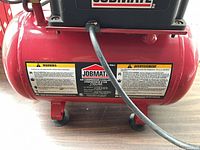 Front view showing Jobmate logo, safety labels and red 3-gallon tank