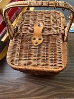 Top view of wicker picnic basket showing lid, leather strap closure and woven pattern