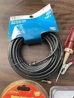 Coiled Commercial Electric RG-6 cable with packaging and spare F connector, red test light partially visible