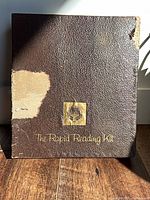 Front of textured brown box with gold logo and title