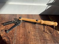 Side view showing full length of wood handle and metal throwing arm