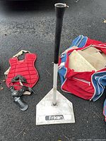 Tee, chest protector, catcher’s mask, shin guard, portion of red duffle bag