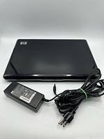 Closed HP Pavilion dv6000 laptop with HP logo and accompanying AC adapter