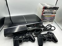PlayStation 3 console with two controllers and stacked games