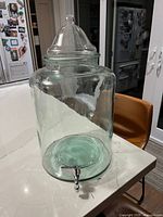 Full view of glass dispenser with lid and spigot on countertop