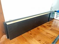 Both dark brown Ikea floating shelves leaning against wall on wood floor