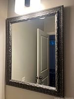 Full view of mirror showing ornate silver-grey frame and reflective surface.