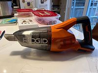 Left side view of Ridgid cordless handheld vacuum showing clear dust chamber and nozzle